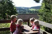 KInderen zitten op het terras bij 1 van de bungalows