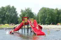 Kinderen glijden van de glijbaan in het waterplas